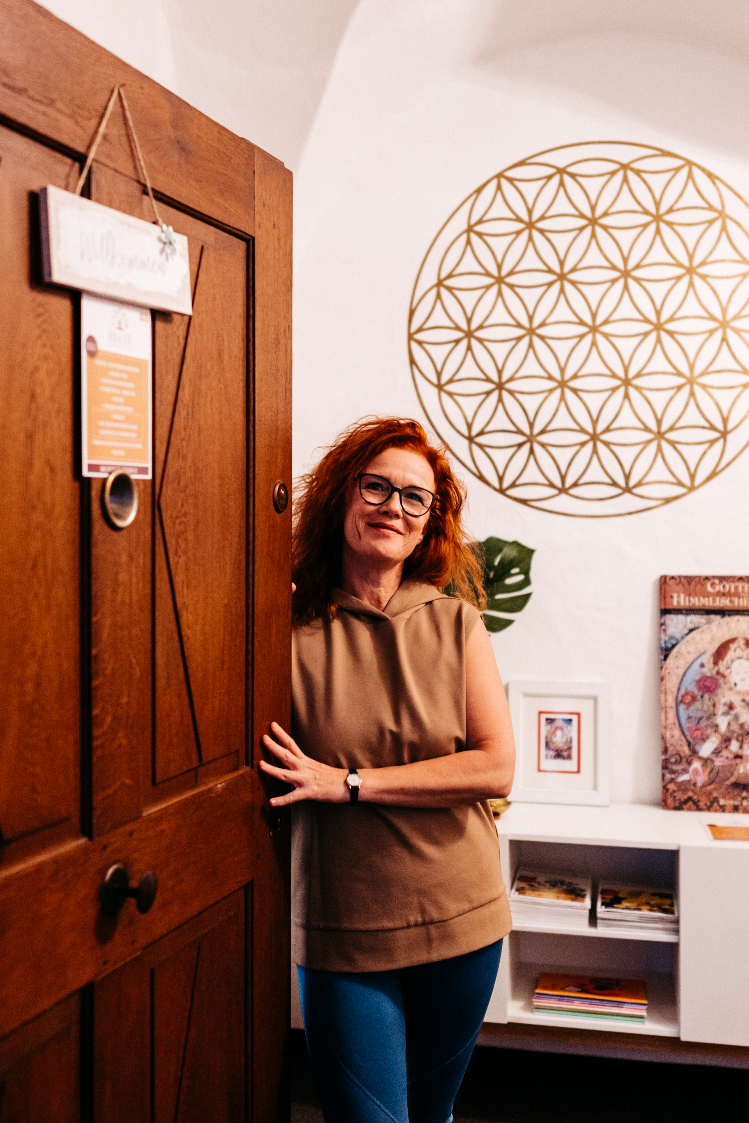 Yoga - Herzliches Willkommen: Yoga-Lehrerin Izabela Schmidt empfängt Besucher an der Tür des gemütlichen Yogastudios „Hier & Jetzt“ mit der Blume des Lebens im Hintergrund. - Hier & Jetzt – Yogastudio für Körper, Geist & Seele in Straubing