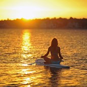 Yoga - Das Zusammenspiel von Kraft, Entspannung und fließenden Bewegungen auf dem Wasser ist ein einzigartiges Erlebnis für alle!

Beim Yoga auf dem SUP Board erlebst du die Wirkungen von Asanas und Pranayama auf einzigartige Weise. Das SUP Board wiegt sanft auf dem Wasser, und du achtest auf deine Mitte, um dir sicheren Halt zu geben. Umgeben von der Landschaft des Sees und frischer Luft bist du dennoch immer in Bewegung, du schaust in den Himmel und grüßt bei schönem Wetter die Sonne mit dem Sonnengruß. - Elvira Weingärtner - Yoga + Retreats im Spreewald