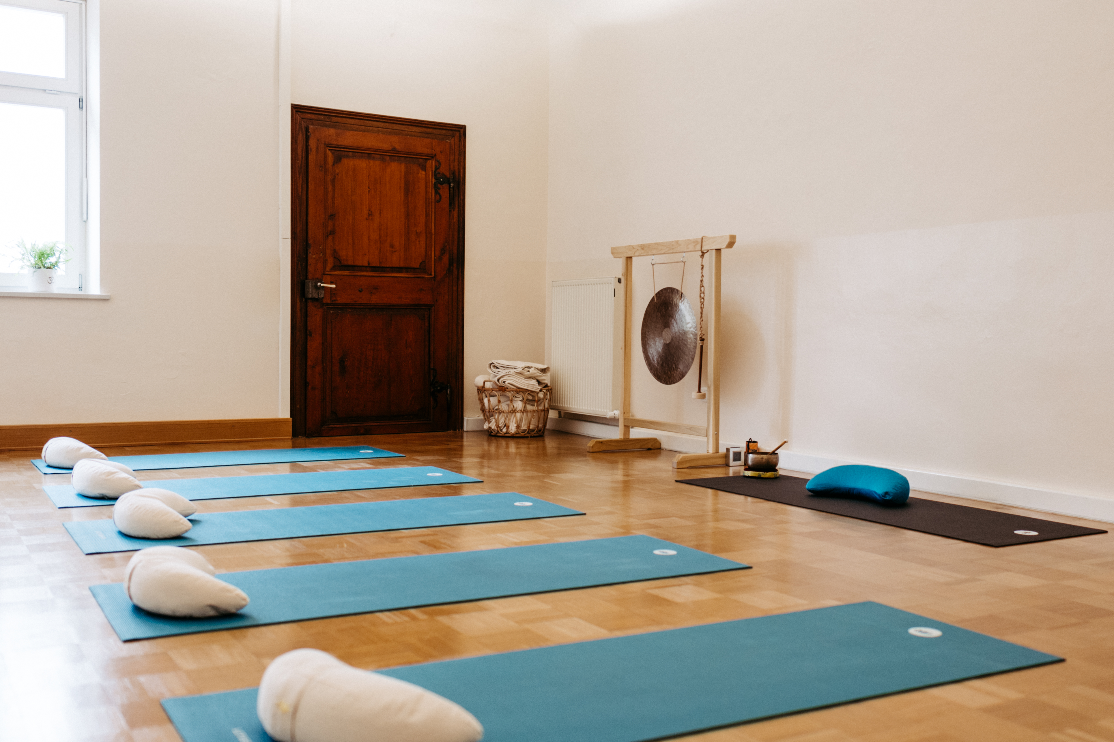 Yoga: Harmonische Wohlfühlatmosphäre: Der Kursraum im Studio „Hier & Jetzt“ ist mit blauen Matten, Kissen, Klangschalen und einem großen Gong für die nächste Yoga-Stunde vorbereitet. - Hier & Jetzt – Yogastudio für Körper, Geist & Seele in Straubing